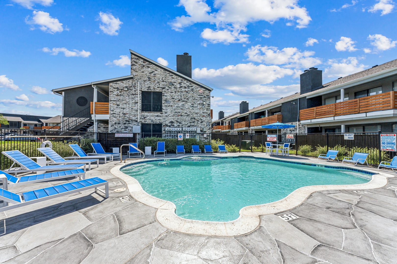 a beach with a pool, chairs, and tables